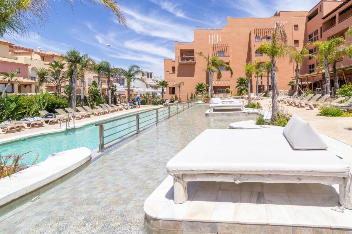 un complejo con piscina con cama y sillas en Tarifa Lances by QHotels, en Tarifa