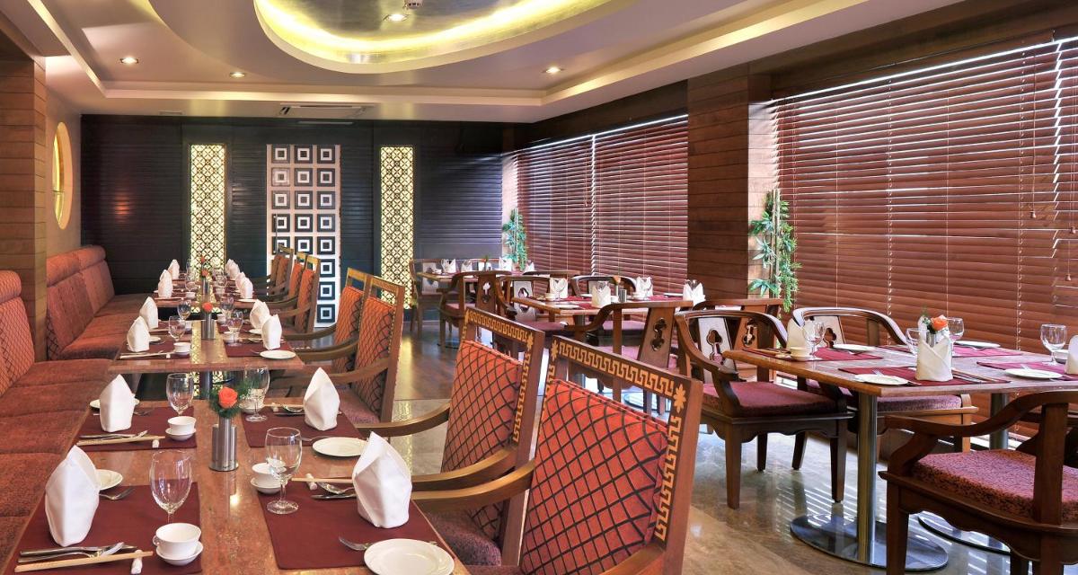 a restaurant with wooden tables and chairs in a room at Fortune JP Palace, Mysore - Member ITC Hotels' Group in Mysore