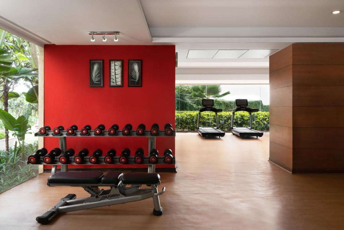 a gym with a red wall and a rack of wine bottles at Hyatt Pune in Pune