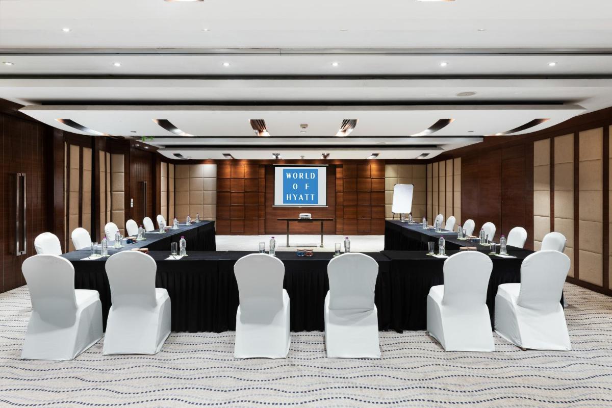 a meeting room with a long table and white chairs at Hyatt Pune in Pune