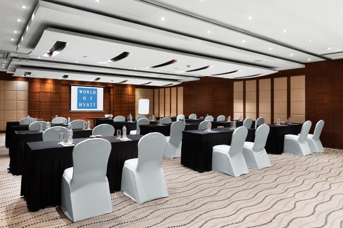 a conference room with tables and chairs and a screen at Hyatt Pune in Pune