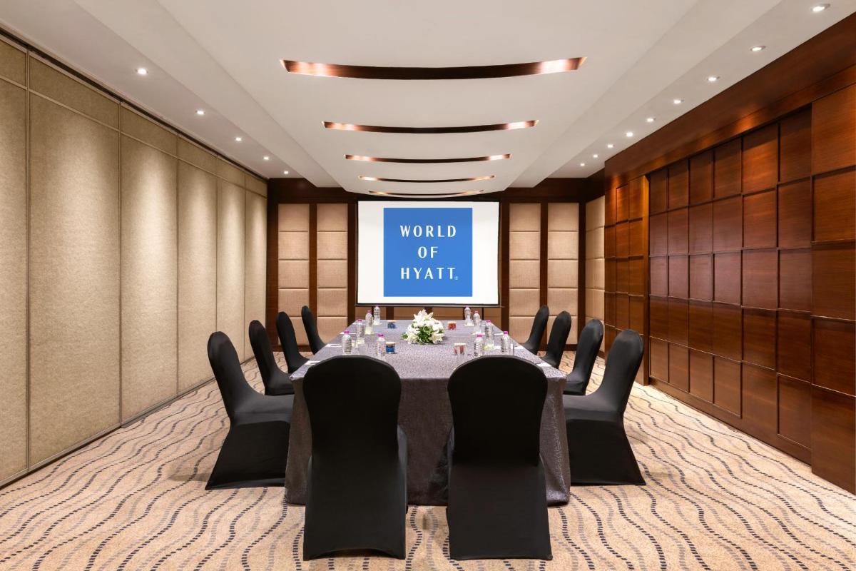 a conference room with a table and chairs and a screen at Hyatt Pune in Pune