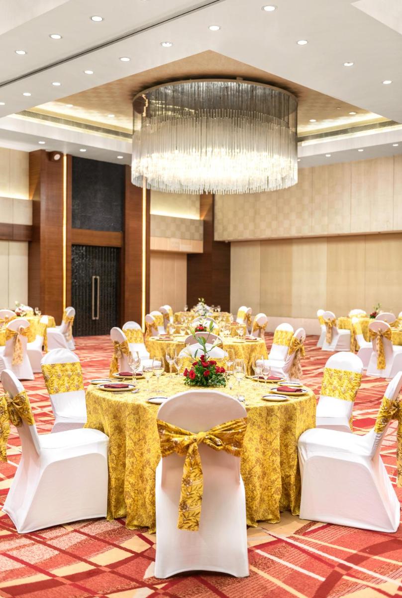 a banquet hall with tables and chairs and a chandelier at Hyatt Pune in Pune