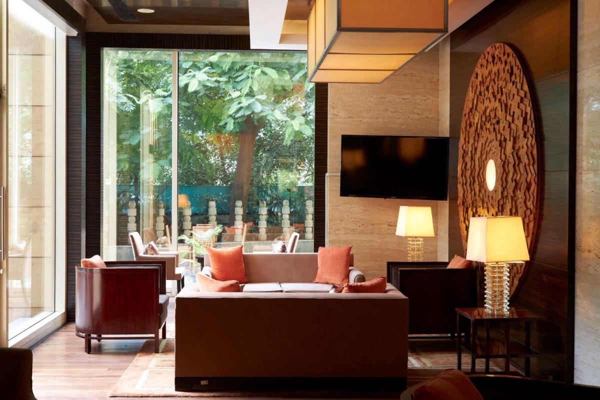 a lobby with a couch and chairs and a large window at Hyatt Regency Pune Hotel & Residences in Pune