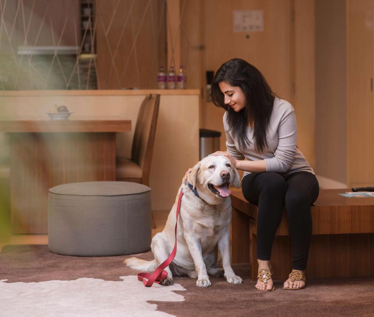 a woman sitting on a bench with a dog at Hyatt Regency Pune Hotel & Residences in Pune