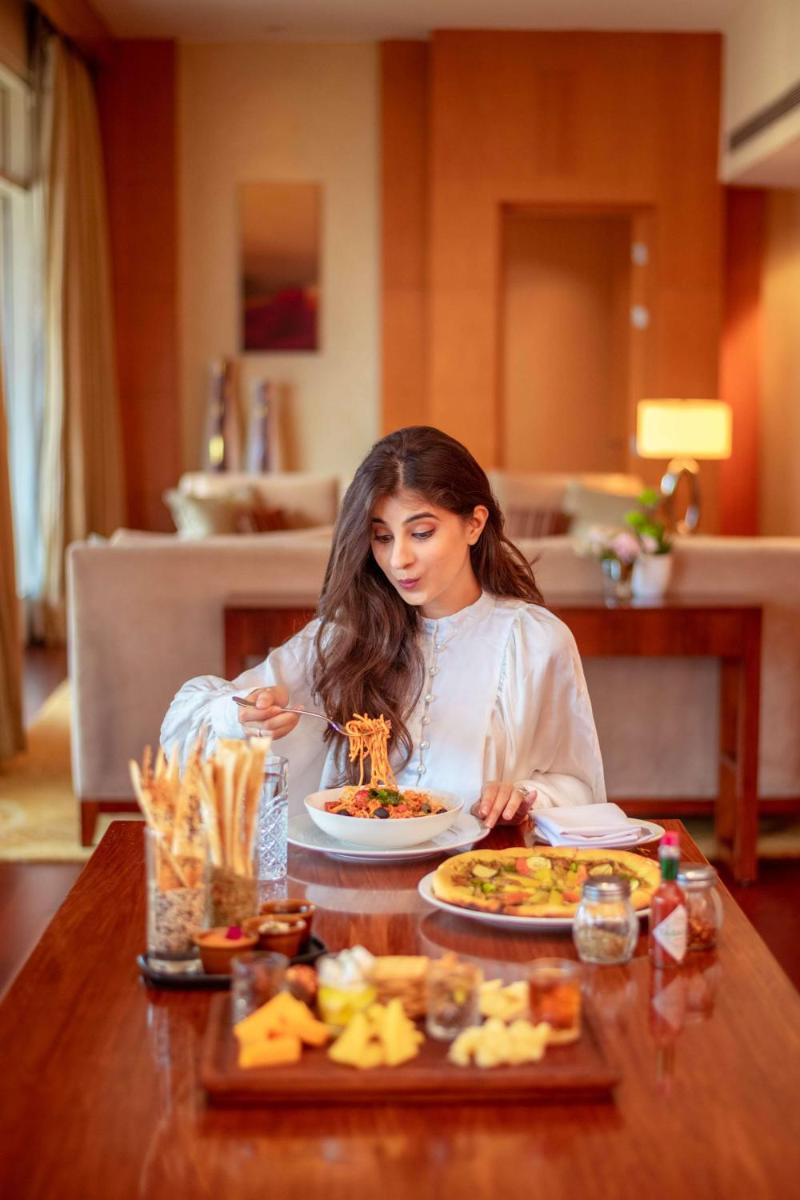 a woman sitting at a table with a plate of food at Hyatt Regency Pune Hotel & Residences in Pune