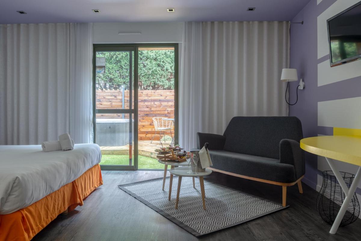 une chambre avec un lit, un canapé et une chaise dans l'établissement Logis Hôtel Domaine du Moulin Cavier - Restaurants & Spa, à Avrillé
