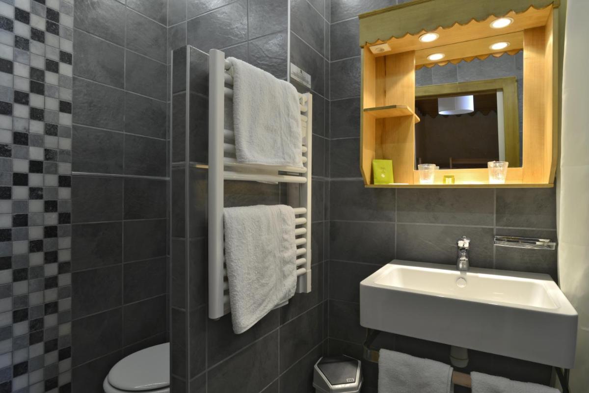 une salle de bain avec un lavabo, des toilettes et un miroir dans l'établissement Hotel Le Ferraillon, à Abondance