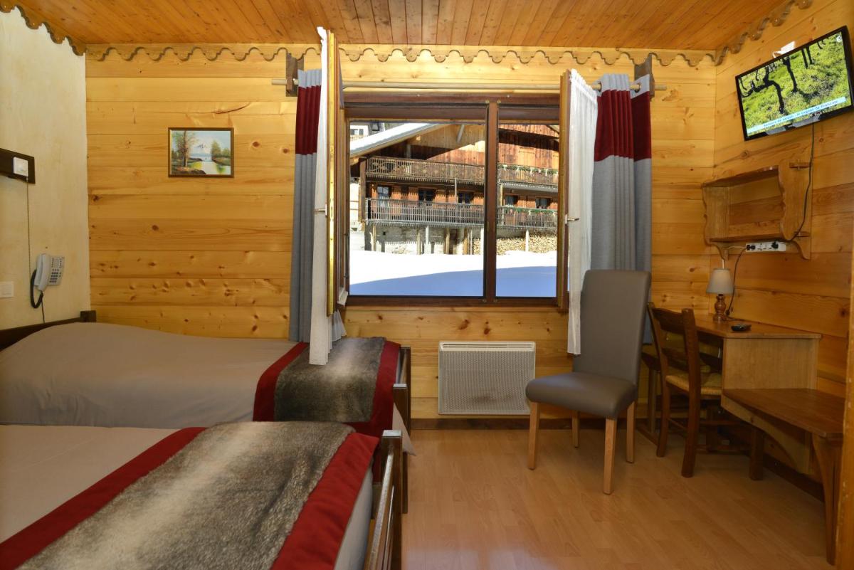 une chambre avec un lit, un bureau et une fenêtre dans l'établissement Hotel Le Ferraillon, à Abondance