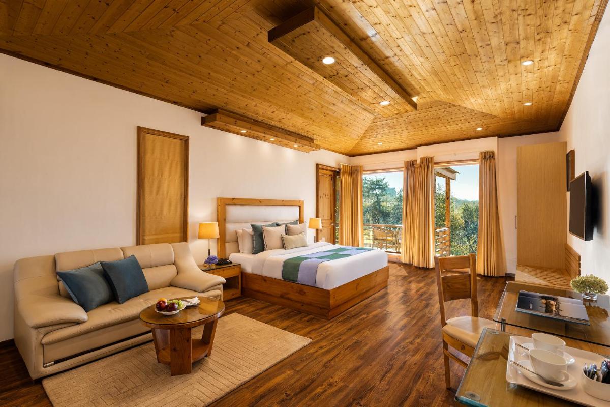a bedroom with a bed and a couch in a room at Baragarh Resort & Spa, Manali- IHCL SeleQtions in Manāli a bedroom with a bed and a couch in a room at Baragarh Resort & Spa, Manali- IHCL SeleQtions in Manāli