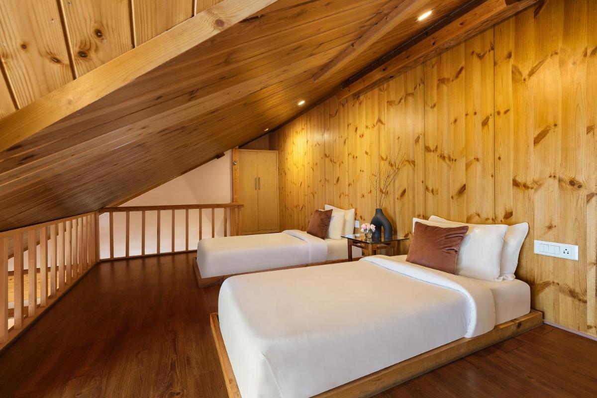 two beds in a room with wooden walls at Baragarh Resort & Spa, Manali- IHCL SeleQtions in Manāli