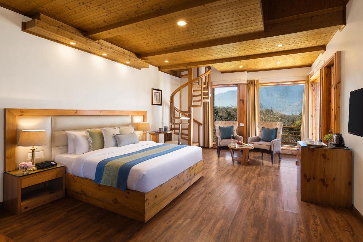 a bedroom with a large bed and a staircase at Baragarh Resort & Spa, Manali- IHCL SeleQtions in Manāli