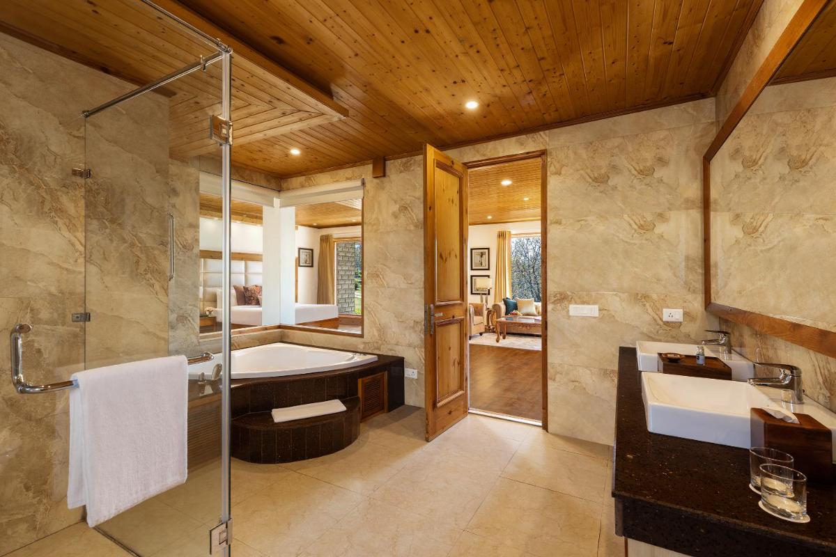 a bathroom with a tub and a sink and a shower at Baragarh Resort & Spa, Manali- IHCL SeleQtions in Manāli a bathroom with a tub and a sink and a shower at Baragarh Resort & Spa, Manali- IHCL SeleQtions in Manāli