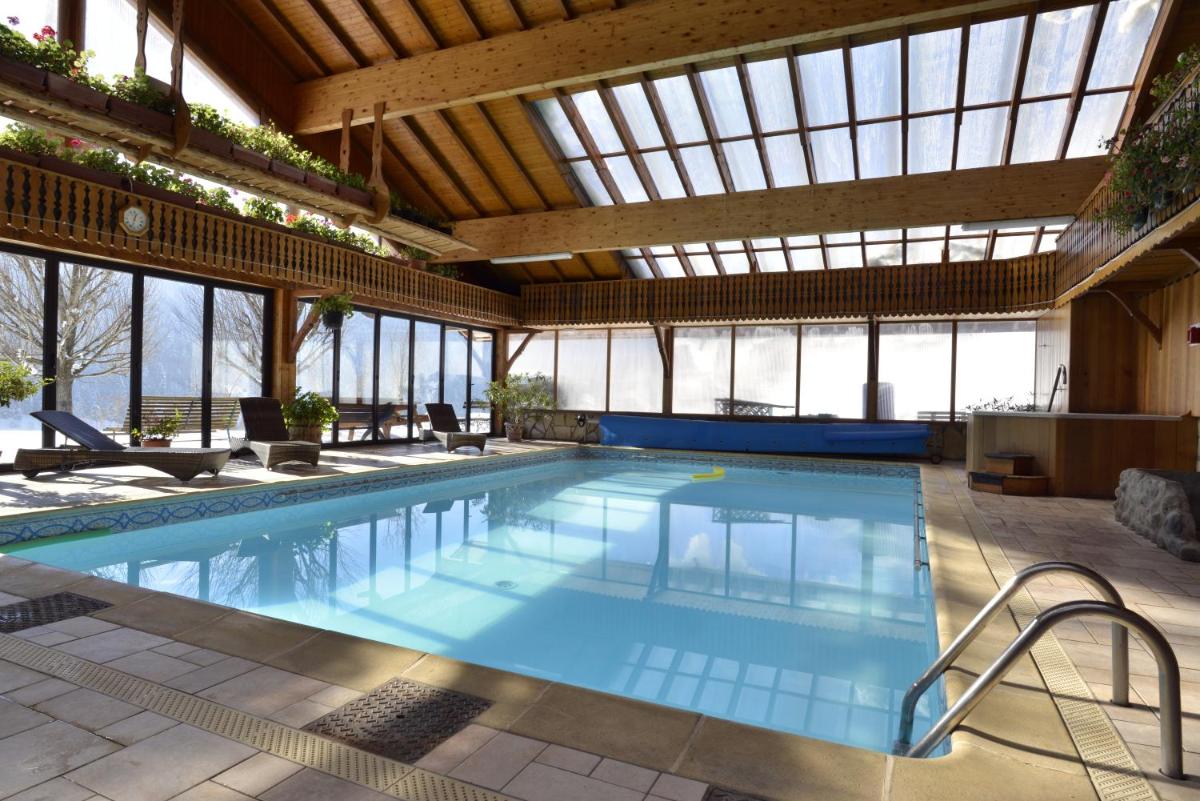 une piscine intérieure avec un grand bâtiment doté de fenêtres dans l'établissement Hotel Le Ferraillon, à Abondance