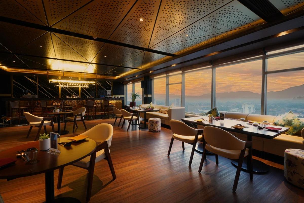 a restaurant with tables and chairs and large windows at Crowne Plaza Kochi by IHG in Cochin