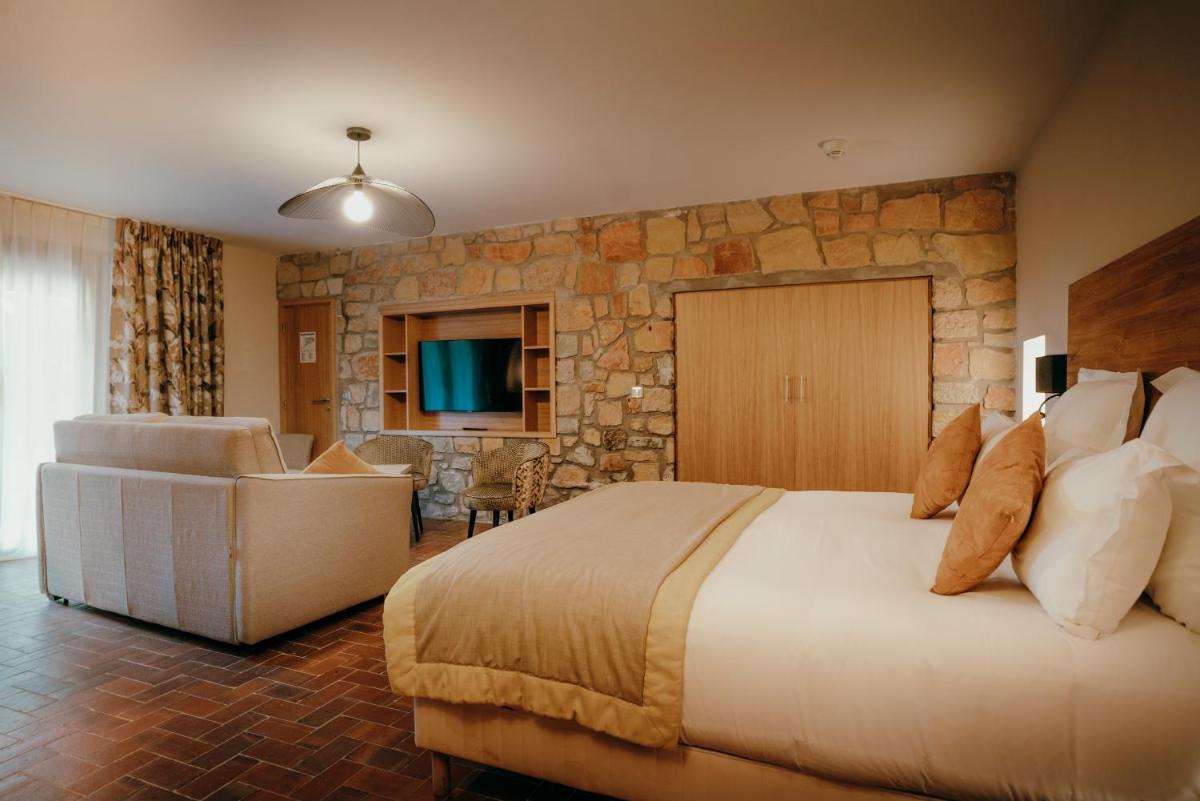 une chambre avec un grand lit et un mur en pierre dans l'établissement Ermitage de l'Oasis & Spa - Cannes Mandelieu, à Mandelieu-la-Napoule 103 autres photos