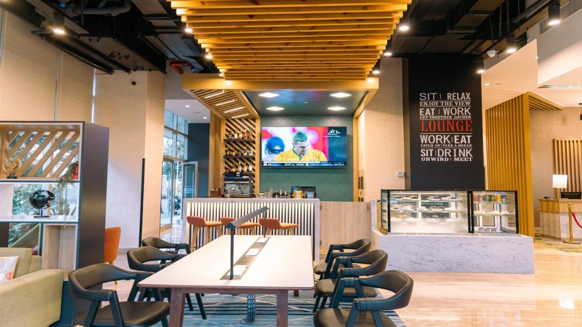 a restaurant with a table and chairs and a tv at Holiday Inn Bengaluru Racecourse by IHG in Bengaluru a restaurant with a table and chairs and a tv at Holiday Inn Bengaluru Racecourse by IHG in Bengaluru