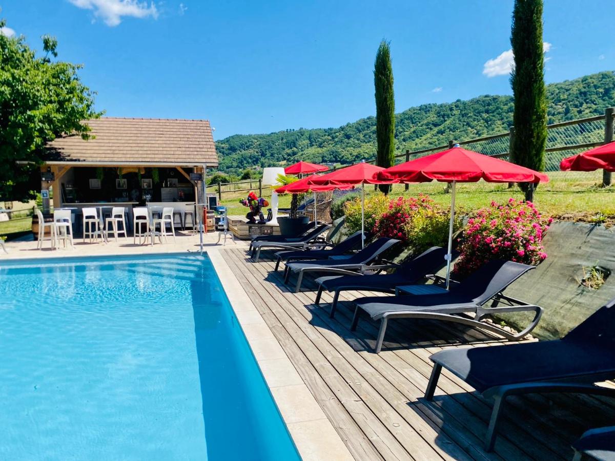 une piscine avec chaises longues et parasols dans l'établissement Domaine de Suzel, à Vignieu