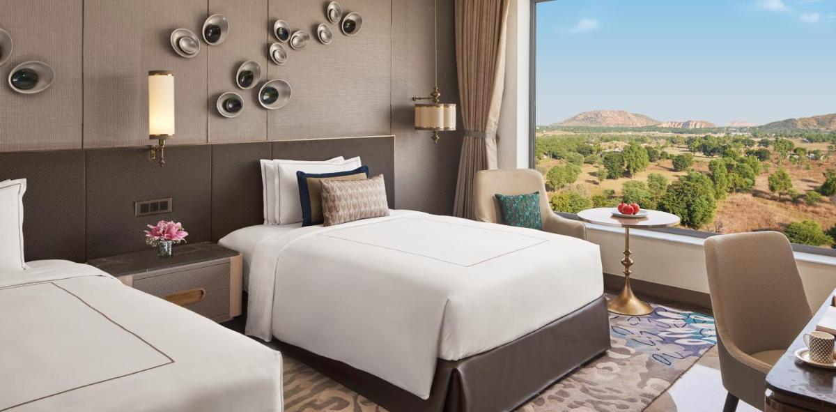 a hotel room with two beds and a window at Taj Amer, Jaipur in Jaipur