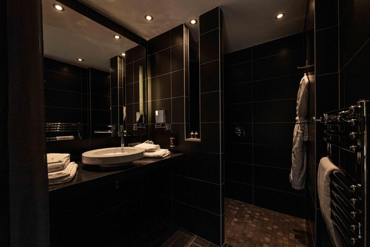 une salle de bain noire avec un lavabo et un miroir dans l'établissement Hôtel Le Parc - La Table de Franck Putelat, à Carcassonne 23 autres photos