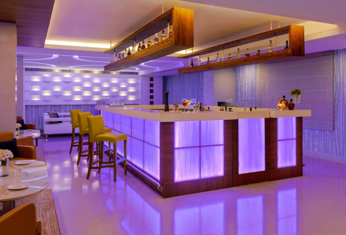 a bar in a restaurant with yellow bar stools at Vivanta Thiruvananthapuram in Trivandrum