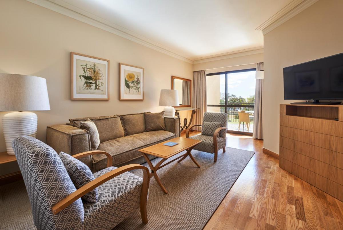 uma sala de estar com um sofá e uma TV em The Residence Porto Mare - PortoBay no Funchal
