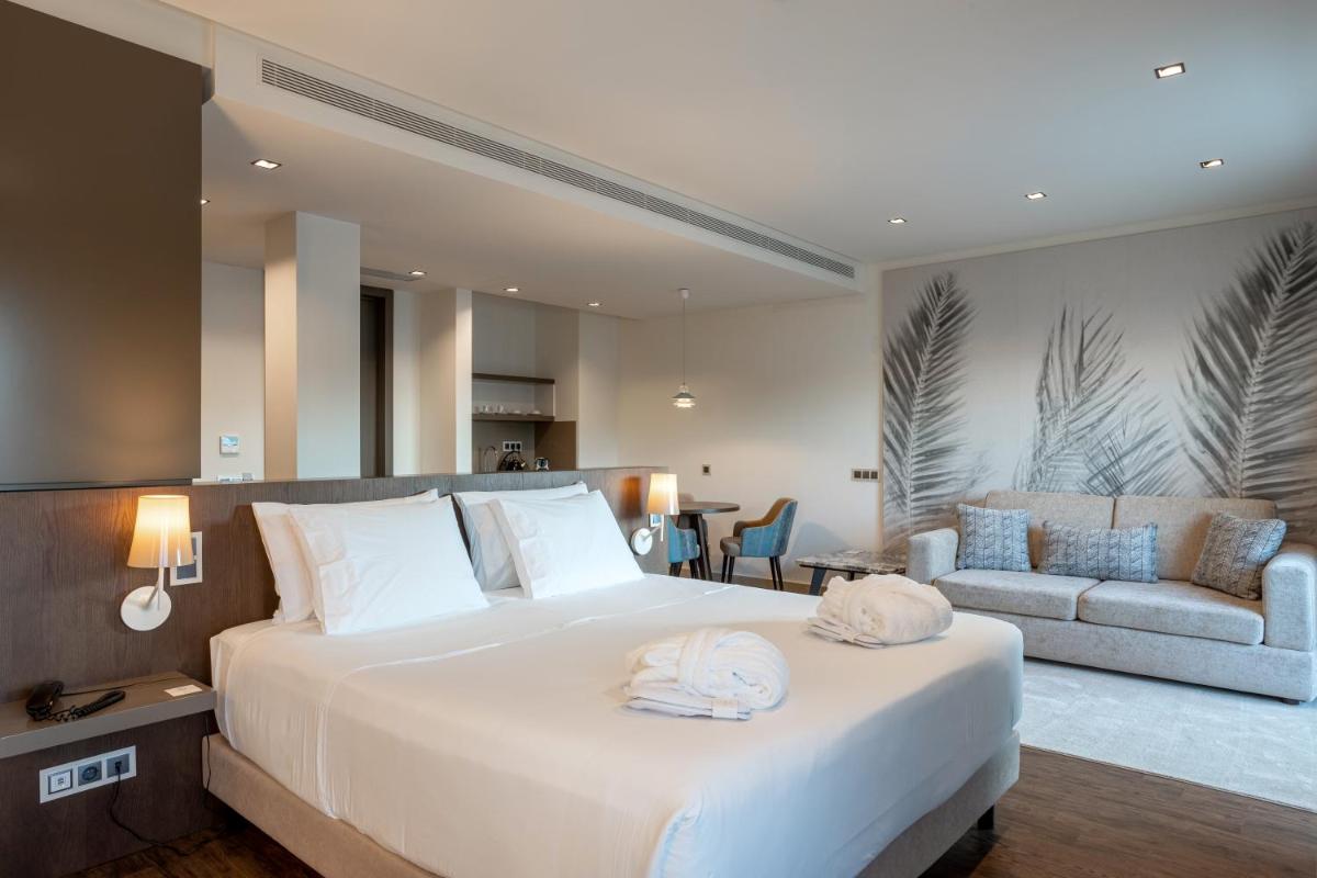 um quarto com uma grande cama branca e um sofá em Hotel Porta do Sol Conference & SPA em Caminha um quarto com uma grande cama branca e um sofá em Hotel Porta do Sol Conference & SPA em Caminha