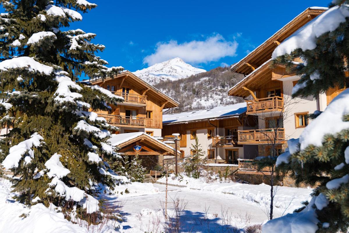 un lodge de ski dans les montagnes avec des arbres enneigés dans l'établissement Lagrange Vacances Le Hameau du Rocher Blanc, à Saint-Chaffrey