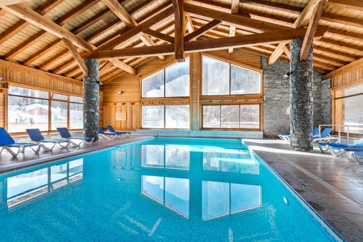 - une piscine avec des chaises bleues dans un bâtiment dans l'établissement Lagrange Vacances Le Hameau du Rocher Blanc, à Saint-Chaffrey