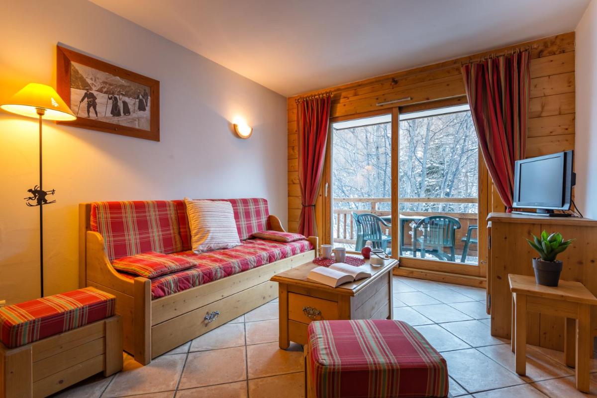 un salon avec un canapé et une télévision dans l'établissement Lagrange Vacances Le Hameau du Rocher Blanc, à Saint-Chaffrey