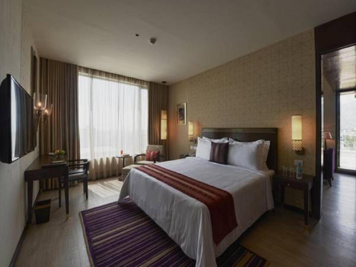 a hotel room with a large bed and a desk at Marasa Sarovar Premiere in Tirupati
