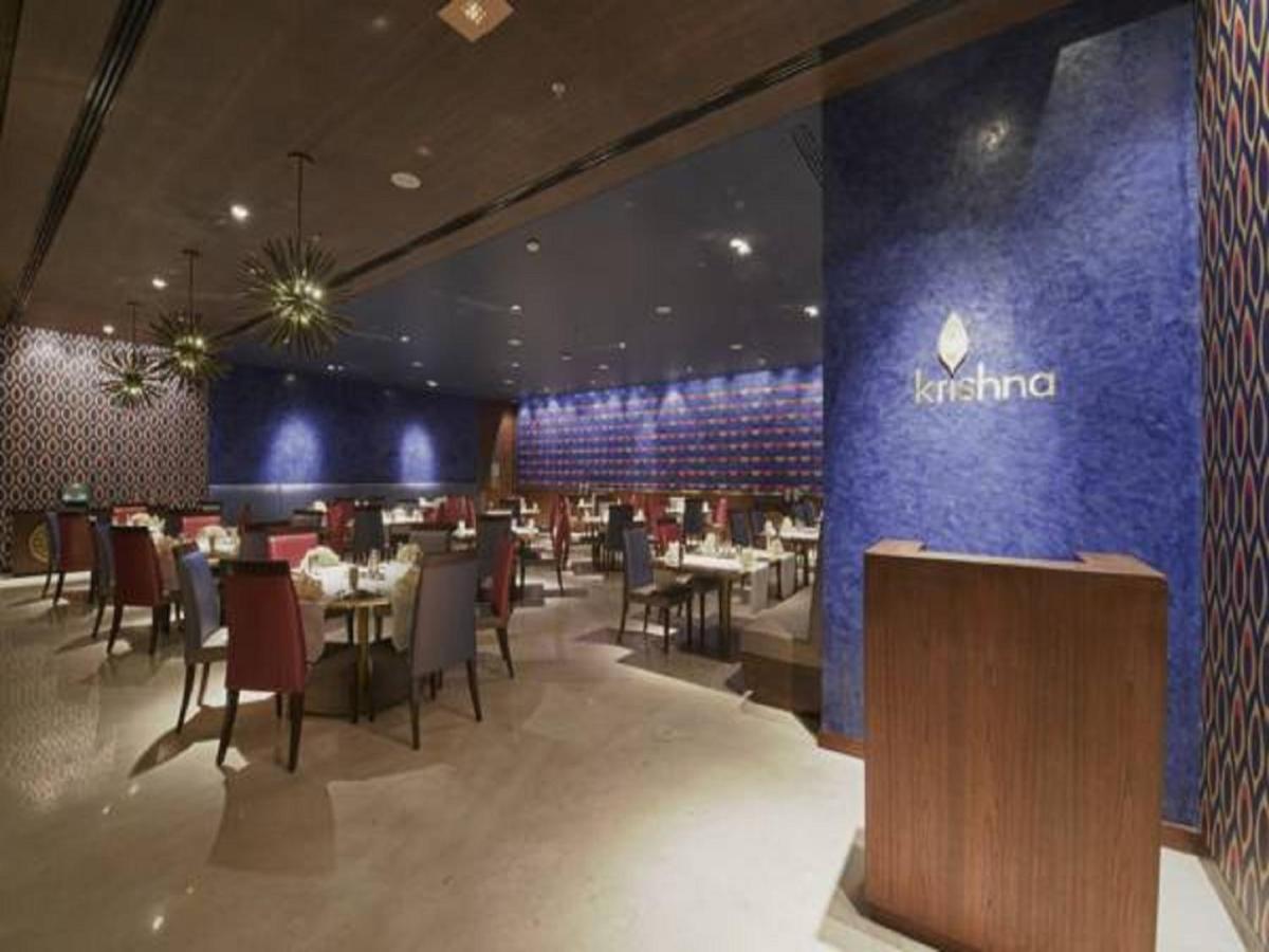 a restaurant with tables and chairs and a blue wall at Marasa Sarovar Premiere in Tirupati
