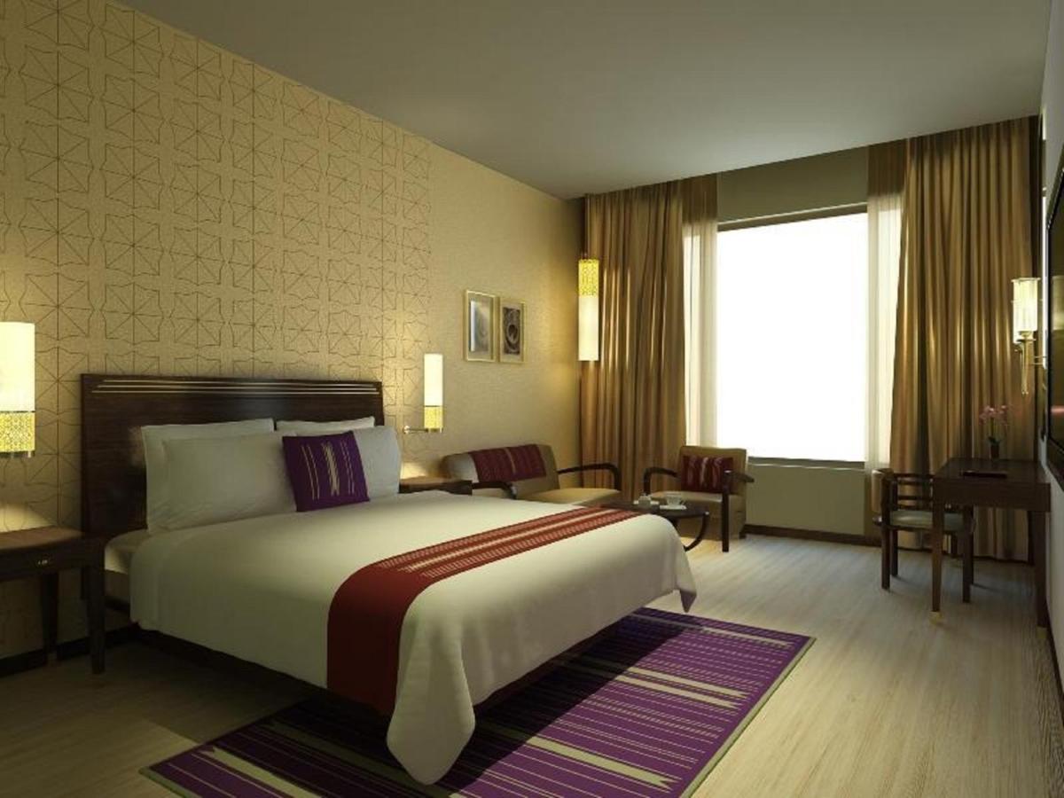 a hotel room with a bed and a large window at Marasa Sarovar Premiere in Tirupati