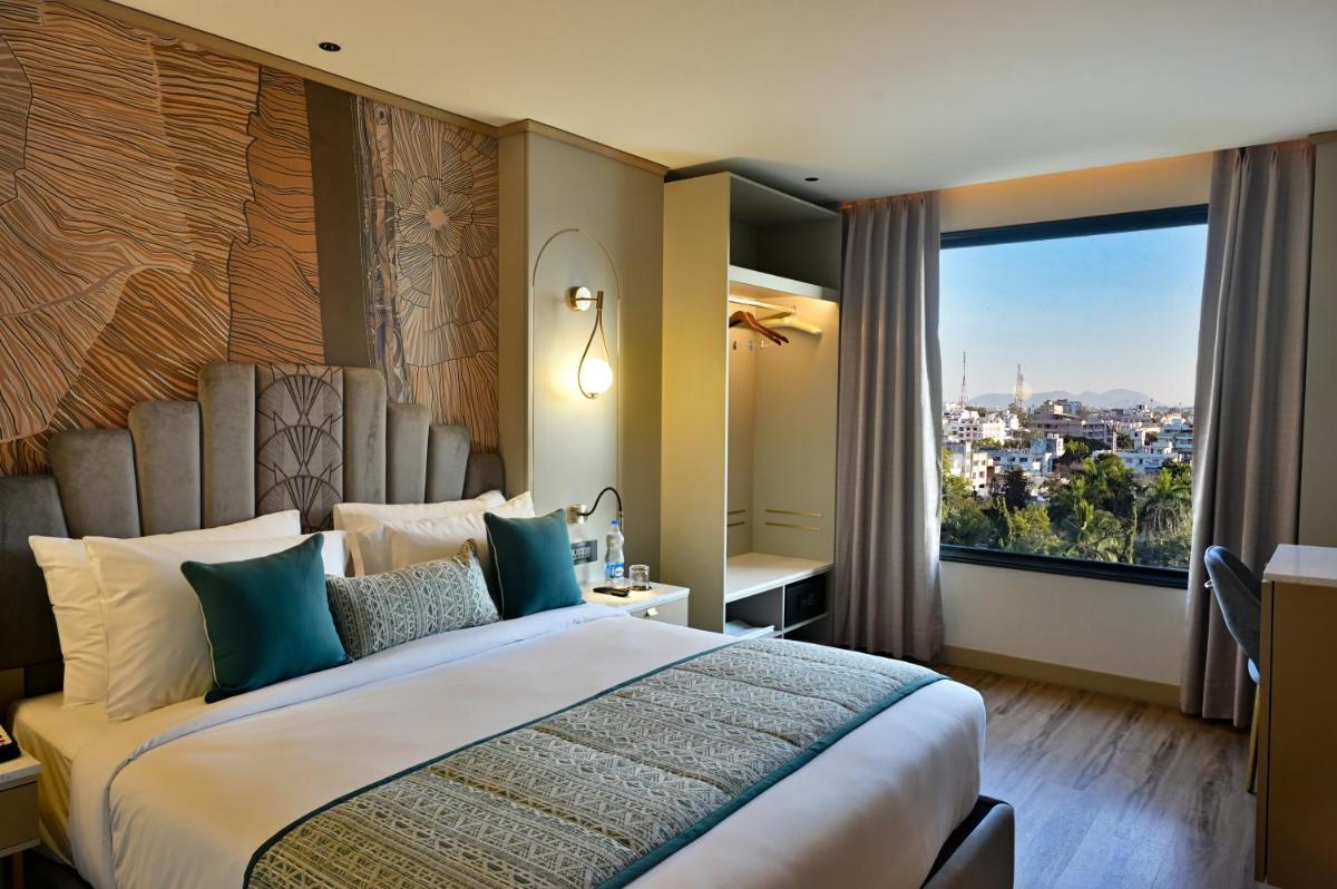 a bedroom with a large bed with a large window at Parallel Hotel Udaipur, a member of Radisson Individuals in Udaipur