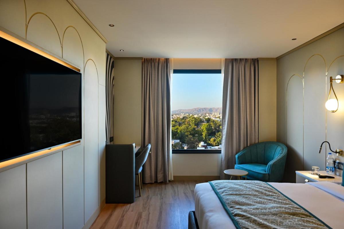 a hotel room with a bed and a large window at Parallel Hotel Udaipur, a member of Radisson Individuals in Udaipur