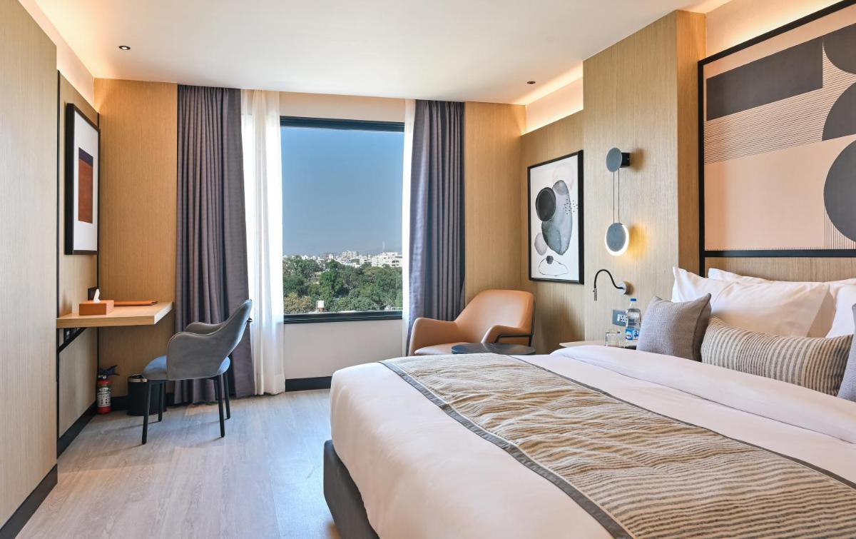 a hotel room with a large bed and a large window at Parallel Hotel Udaipur, a member of Radisson Individuals in Udaipur