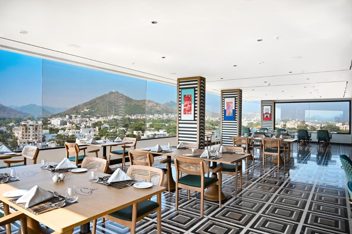 a restaurant with tables and chairs and a view at Parallel Hotel Udaipur, a member of Radisson Individuals in Udaipur