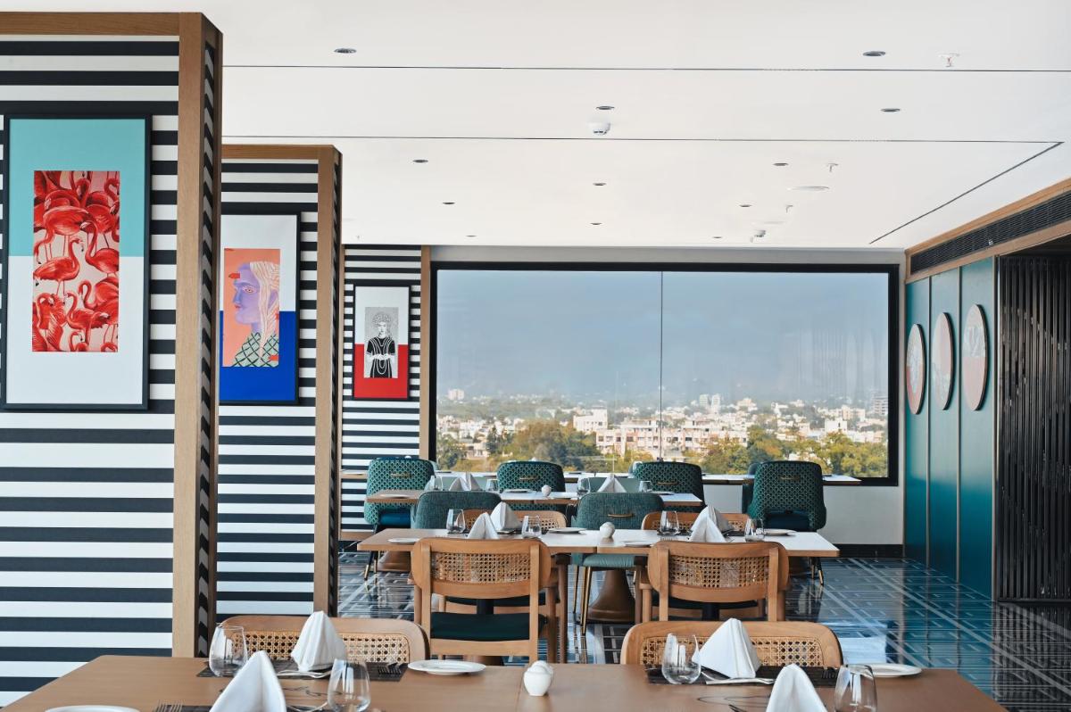 a restaurant with tables and chairs and a large window at Parallel Hotel Udaipur, a member of Radisson Individuals in Udaipur