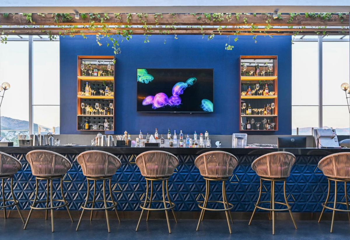 a bar with a blue wall and brown stools at Parallel Hotel Udaipur, a member of Radisson Individuals in Udaipur