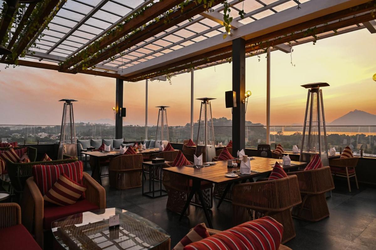 a restaurant with tables and chairs with the sunset in the background at Parallel Hotel Udaipur, a member of Radisson Individuals in Udaipur