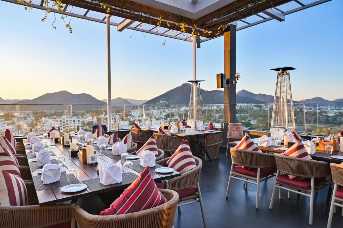a restaurant with tables and chairs and a view of the city at Parallel Hotel Udaipur, a member of Radisson Individuals in Udaipur