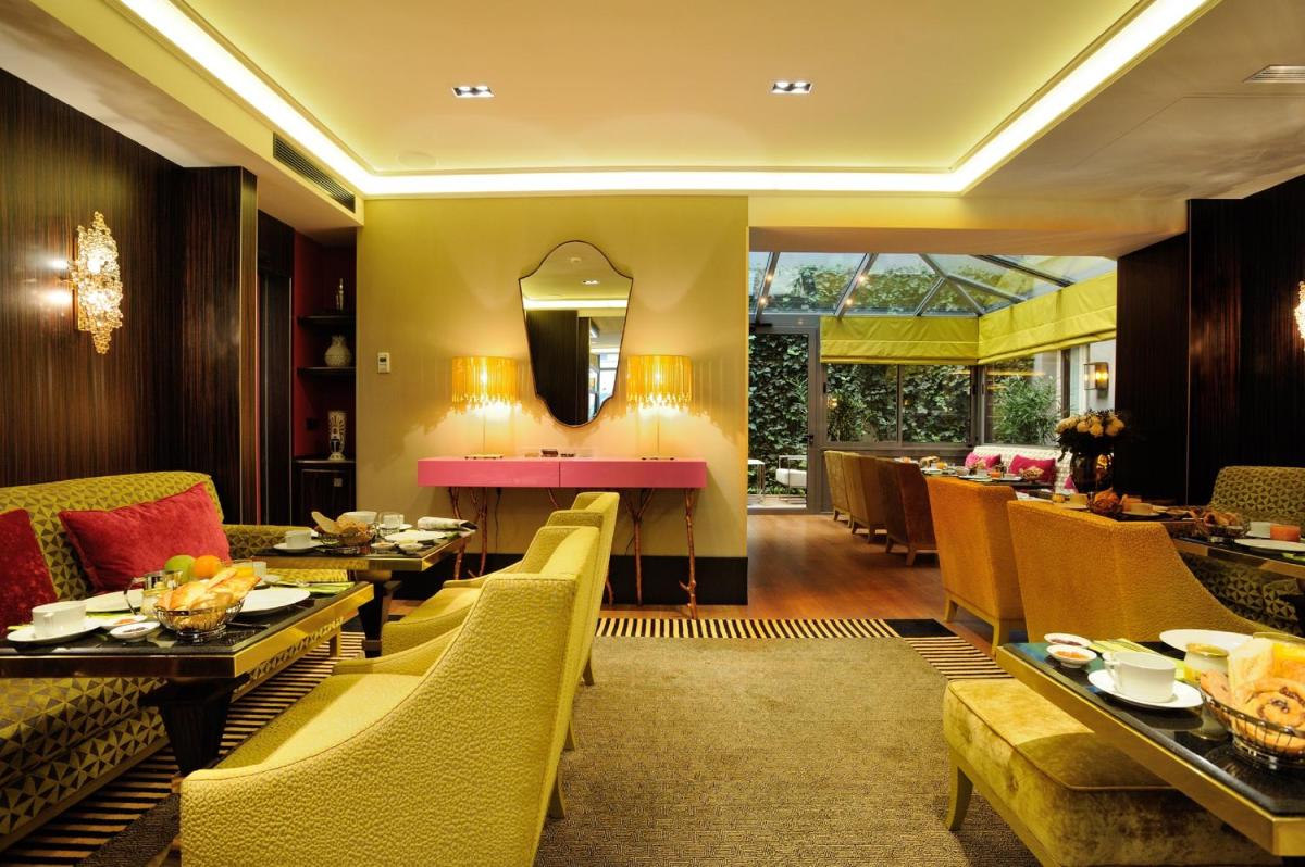 un restaurant avec des tables, des chaises et un miroir dans l'établissement Hôtel Baume, à Paris