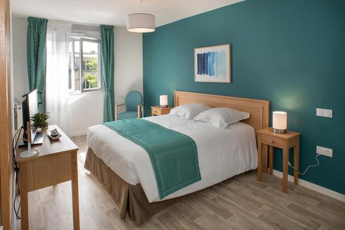 une chambre avec un grand lit avec un mur bleu dans l'établissement DOMITYS L'ALLIACEE - Résidence Services Séniors, à Achères