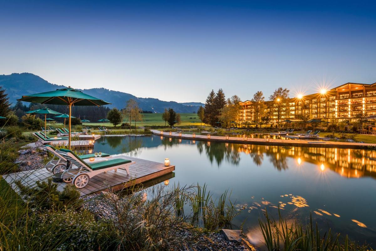 ein Resort mit einem Steg, einem Sonnenschirm und einem See in der Unterkunft Sonnenalp Resort in Ofterschwang
