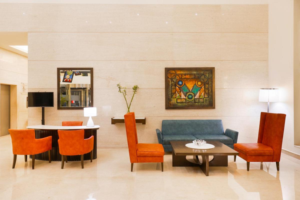 a living room with a couch and a table and chairs at Lemon Tree Premier, Ulsoor Lake, Bengaluru in Bengaluru