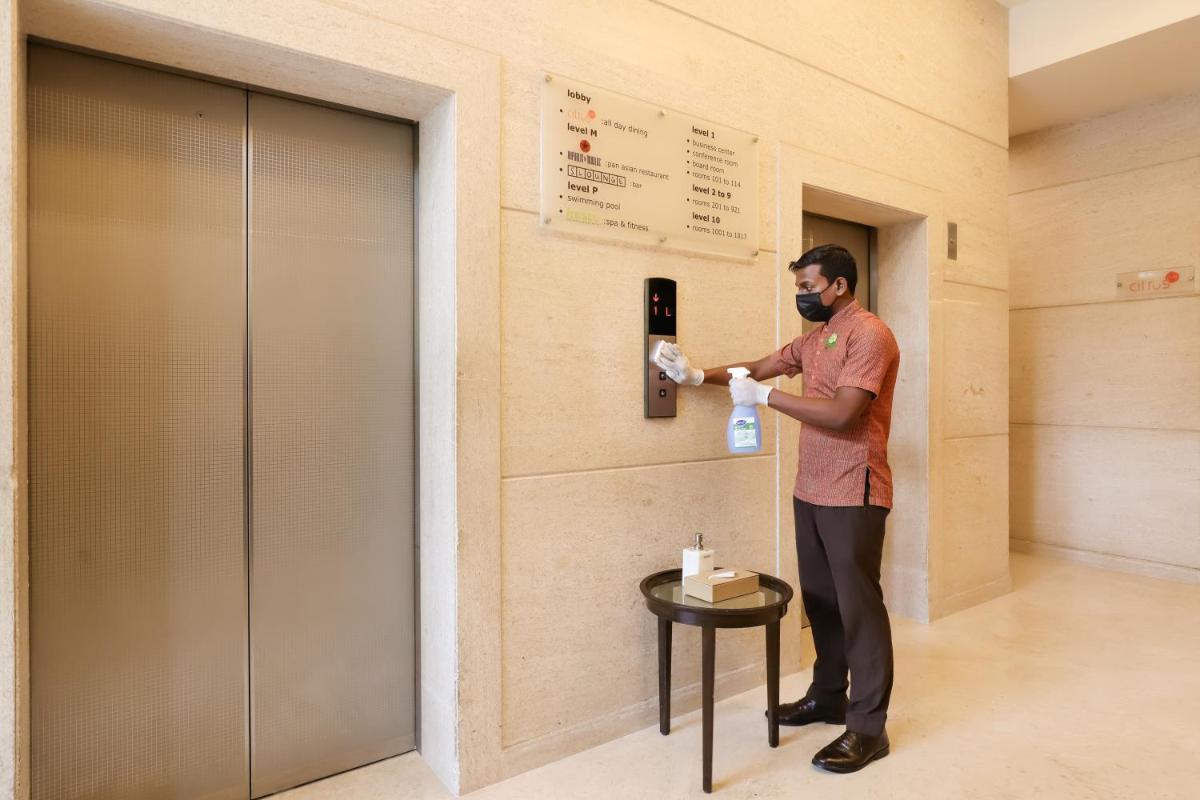 a man is standing in a hallway with a bottle at Lemon Tree Premier, Ulsoor Lake, Bengaluru in Bengaluru