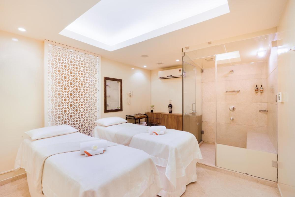 two beds in a room with a shower and a bathroom at Lemon Tree Premier, Ulsoor Lake, Bengaluru in Bengaluru