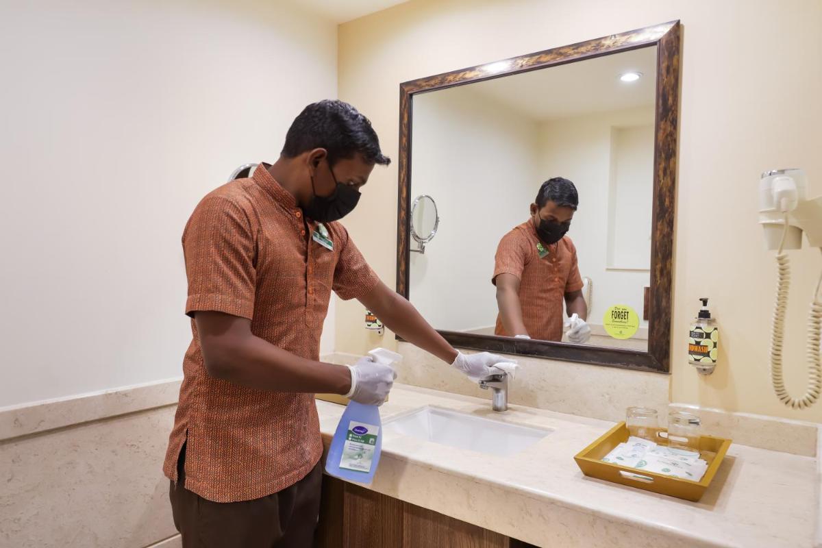 a man is washing his hands in a bathroom sink at Lemon Tree Premier, Ulsoor Lake, Bengaluru in Bengaluru