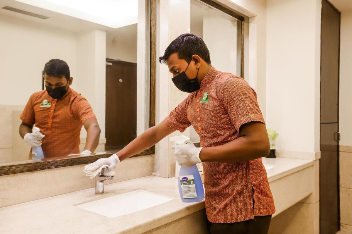 a man is washing his hands in a bathroom sink at Lemon Tree Premier, Ulsoor Lake, Bengaluru in Bengaluru