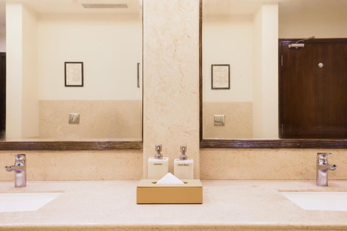 a bathroom with two urinals and a box on the floor at Lemon Tree Premier, Ulsoor Lake, Bengaluru in Bengaluru
